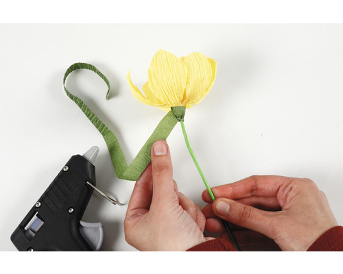 Person tillverkar pappersblomma med limpistol