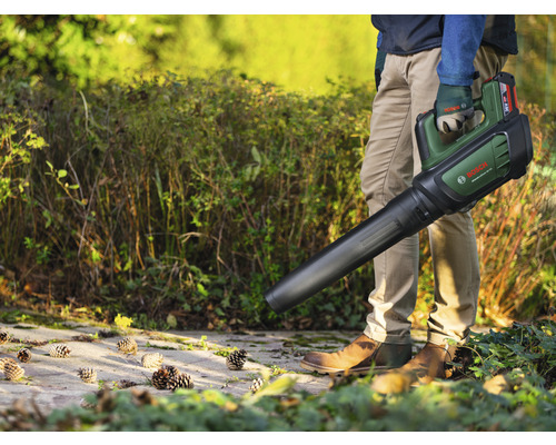 Person håller en batteridriven lövblåsare från Bosch i trädgården.