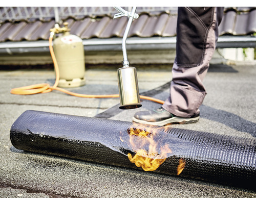 Takläggare svetsar ett takmembran på ett tak med en gasbrännare