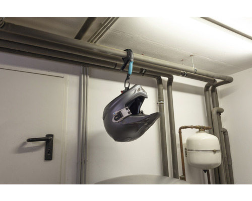 En motocrosshjälm hänger i en rörklämma på ett värmerör.