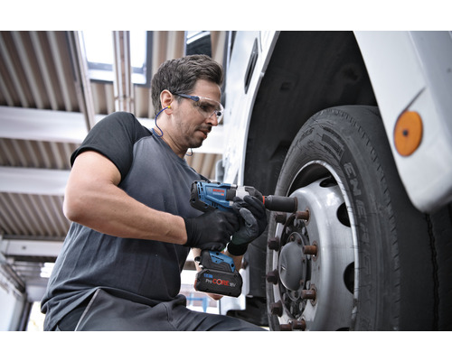En man använder en sladdlös mutterdragare för att fästa ett hjul på ett fordon.