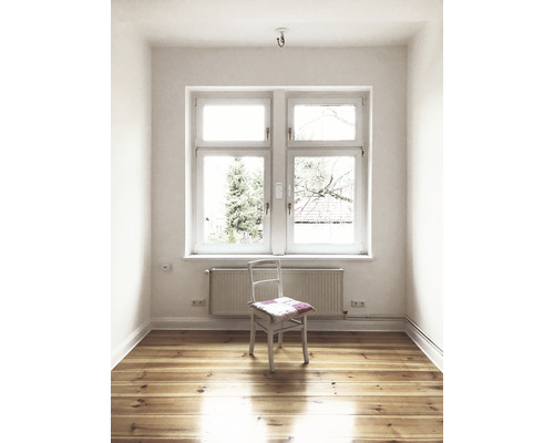 Tomt rum med fönster, element, trägolv och stol