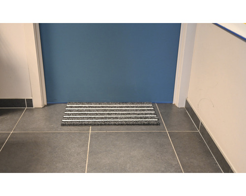 Dörrmatta med ränder framför en dörr på klinkergolv