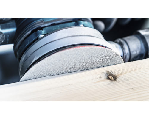 Närbild av en slipmaskin som bearbetar en träbit.