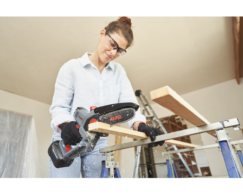 Kvinna sågar trä med en AL-KO batteridriven motorsåg på en arbetsbänk