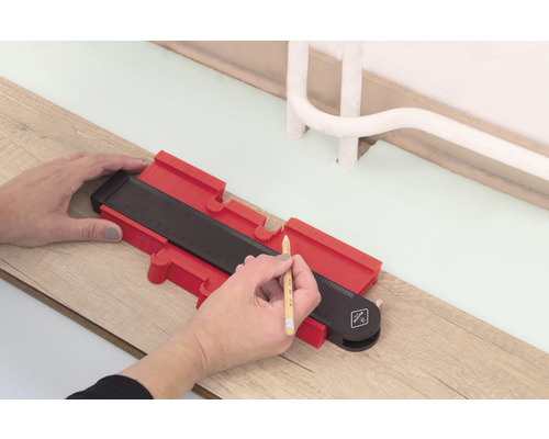 Person använder en konturmall för att rita på ett trägolv