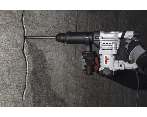 En hand använder en Pattfield PA 1300 rivningshammare på en betongvägg.