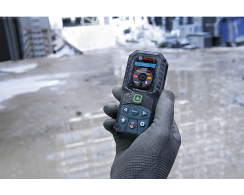 En hand med handske håller en digital avståndsmätare från Bosch.