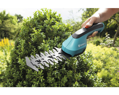Gardena batteridriven busksax trimmar en buske i trädgården.
