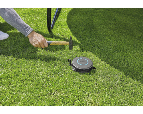 Installation av en Gardena robotgräsklippare med en hammare på gräsmatta.