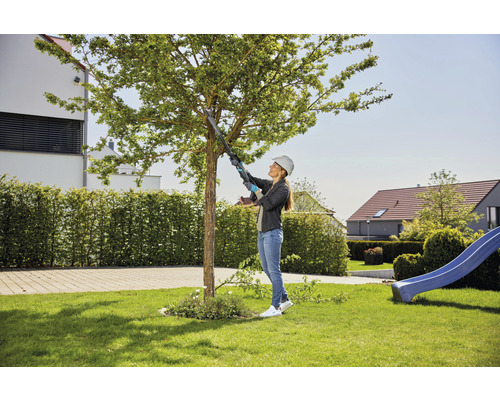 Kvinna med grensax sköter ett träd i trädgården.