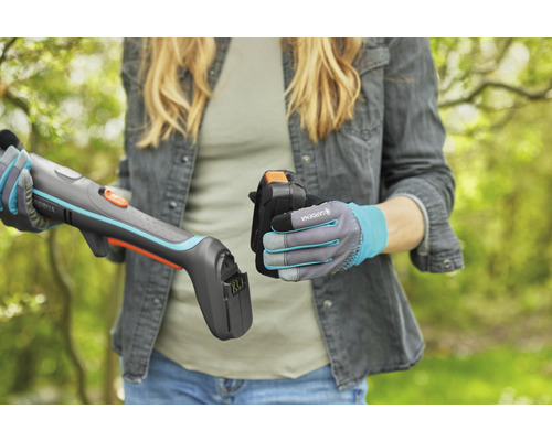 Kvinna sätter i batteriet i en Gardena batteridriven grässax