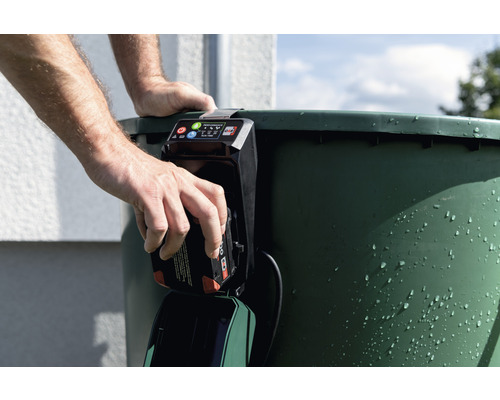 Man sätter in ett batteri i en regnvattentunnspump.