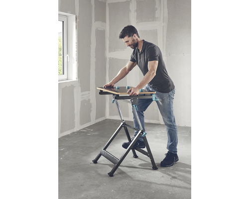 En man använder ett hopfällbart arbetsbord i ett rum.