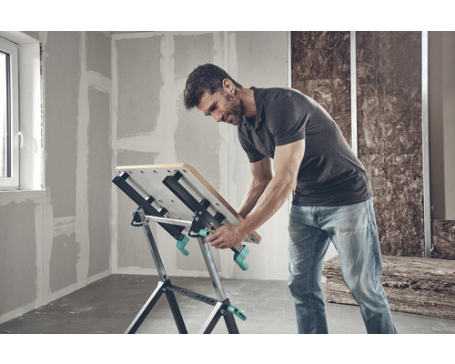 Man som arbetar vid en Wolfcraft arbetsbänk i ett icke-renoverat rum.