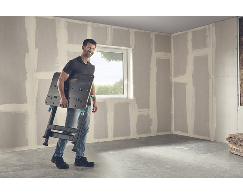 Man bär en Wolfcraft Master 650 arbetsbänk i ett rum med gipsväggar