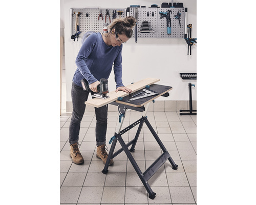 Kvinna arbetar med sticksåg på en arbetsbänk i en verkstad.