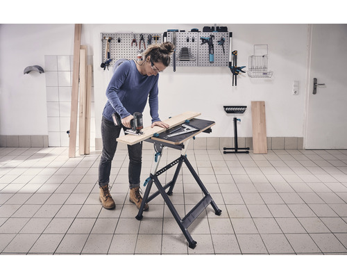 Kvinna sågar trä på en arbetsbänk med en sticksåg i en verkstad