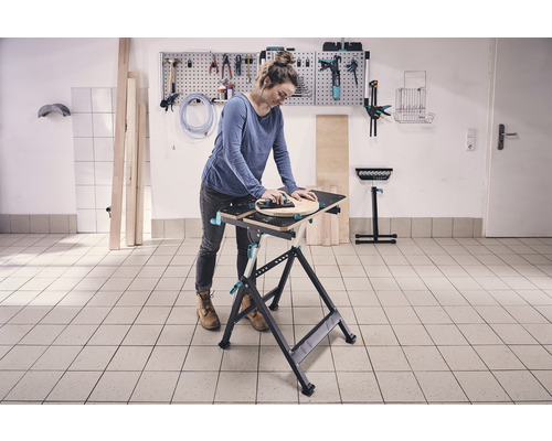 Kvinna som arbetar vid en arbetsbänk med verktyg på väggen