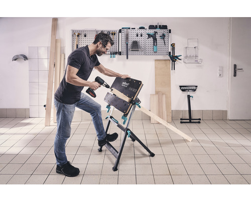 En man borrar ett arbetsstycke med en sladdlös borr på en Wolfcraft Master 600 arbetsbänk.