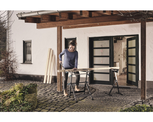 Kvinna sågar trä på en hopfällbar arbetsbänk utomhus.