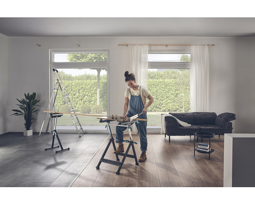 En kvinna sågar trä på en arbetsbänk i ett ljust rum