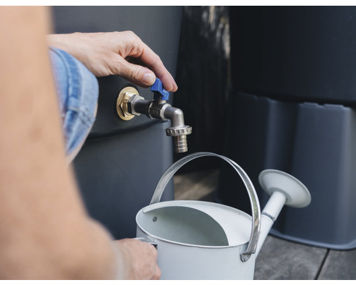 En person fyller en vattenkanna med vatten från en regnvattentunna.