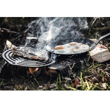 Bacon och stekt ägg tillagas utomhus över öppen eld.