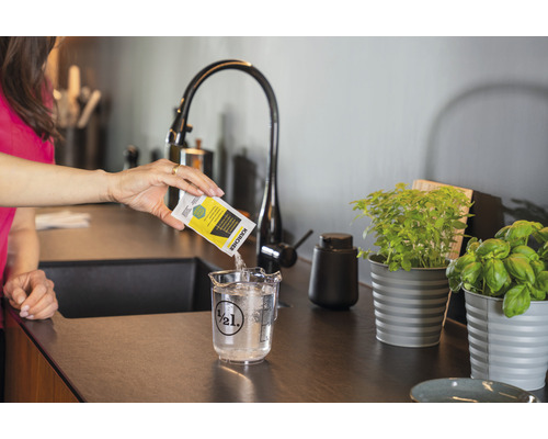 Kvinna häller rengöringsmedel från Kärcher i en måttbägare med vatten.