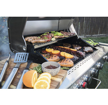 Grill med kött, grönsaker och grilltillbehör på ett träbord