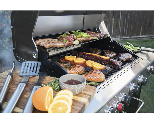 Grill med kött, grönsaker och grilltillbehör på ett träbord