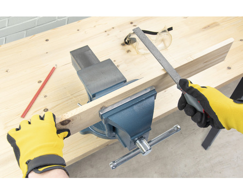 Arbetsbänk med skruvstäd, träbit, fil, penna, skyddsglasögon och arbetshandskar