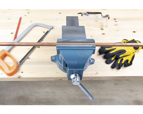 Arbetsbänk med skruvstäd, kopparrör, handsåg, skyddsglasögon och arbetshandskar