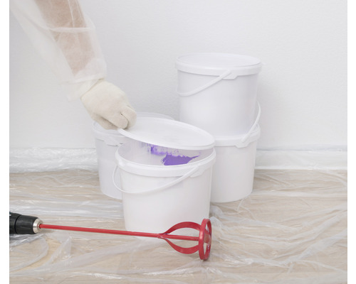 Flera vita färgburkar med färgblandare och täckplast.