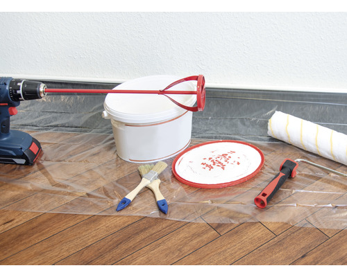 Färghink, omrörare, borrmaskin, färgroller och penslar på en folie