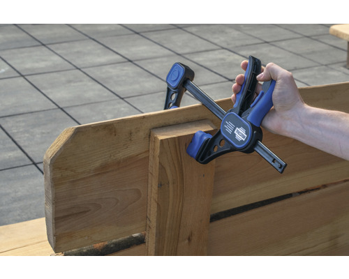 Hand håller en enhandsspännare på trä