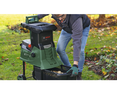 Trädgårdsscen med en man som använder en kompostkvarn och tömmer en uppsamlingsbehållare. Bosch logotyp.