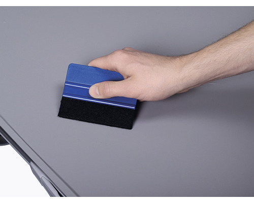 Hand använder skrapa för att jämna ut en yta