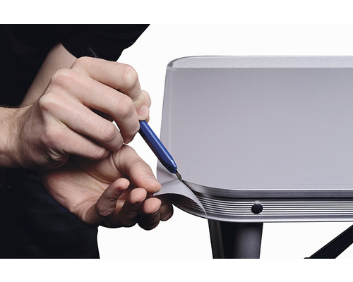 En person skär folie på en yta med en kniv.