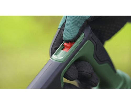 Detaljbild av hantering av ett trädgårdsredskap med röd strömbrytare