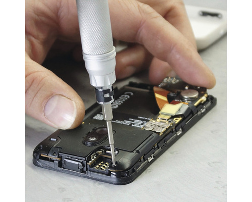 En man reparerar en smartphone med en skruvmejsel