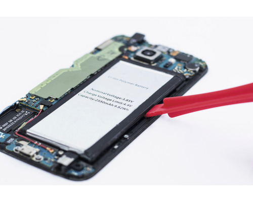 Öppnad smartphone med borttaget batteri och rött verktyg
