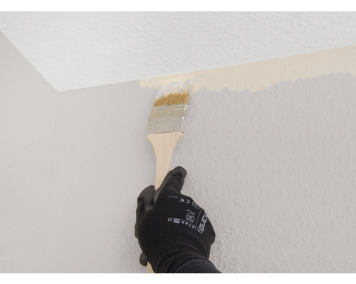 Person målar vägg med pensel