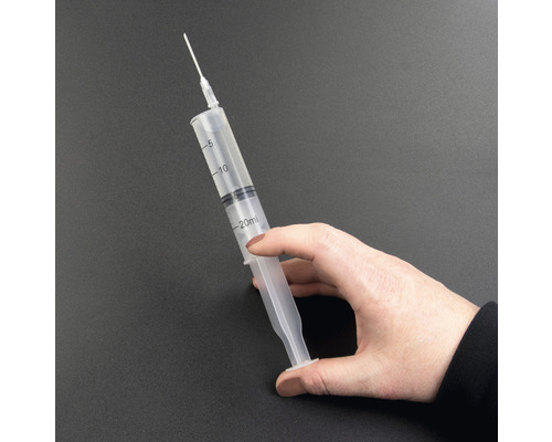 En hand håller en 20 milliliters spruta med nål.