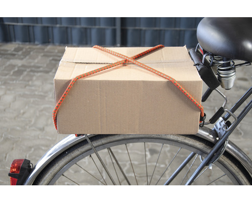 En kartong är fastsatt på en cykel med en bagagerem.