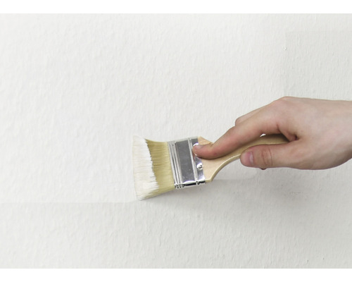 En person målar en vägg med en pensel.