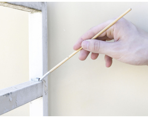 Hand målar ett metallgaller med pensel