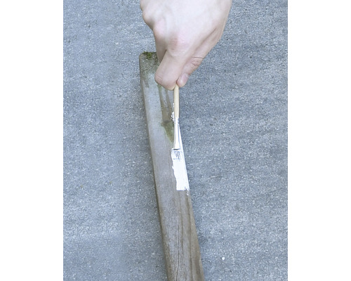 Målning av en trästolpe med en pensel