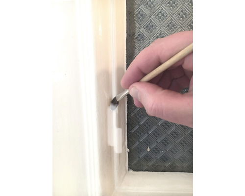 En pensel används för att applicera färg på en fönsterkarm.