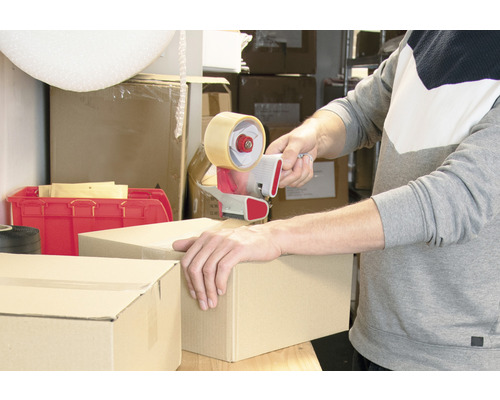 En person försluter en kartong med en tejpdispenser.